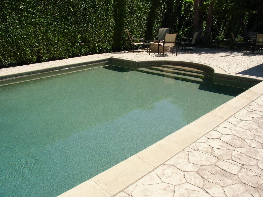 a swimming pool with stamped concrete walkway